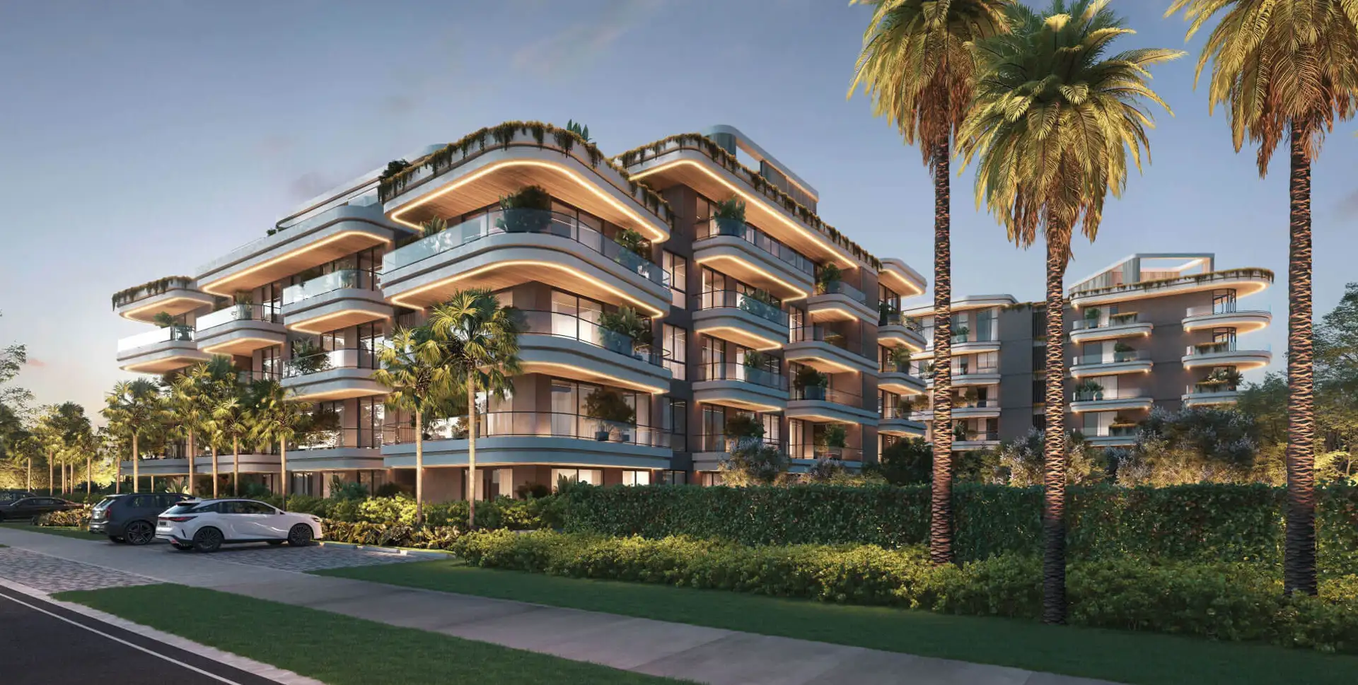Luxury residential buildings of ELITE Cap Cana at dusk, framed by palm trees and gardens